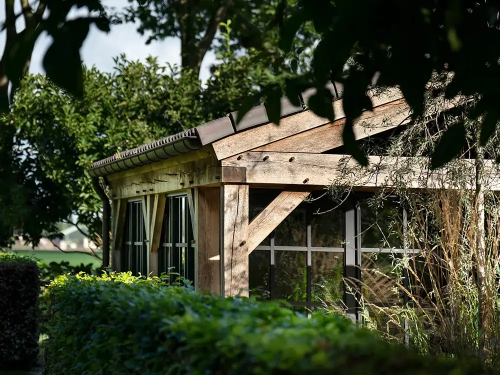 Klein eikenhouten gebouw tussen bomen met grote glazen ramen