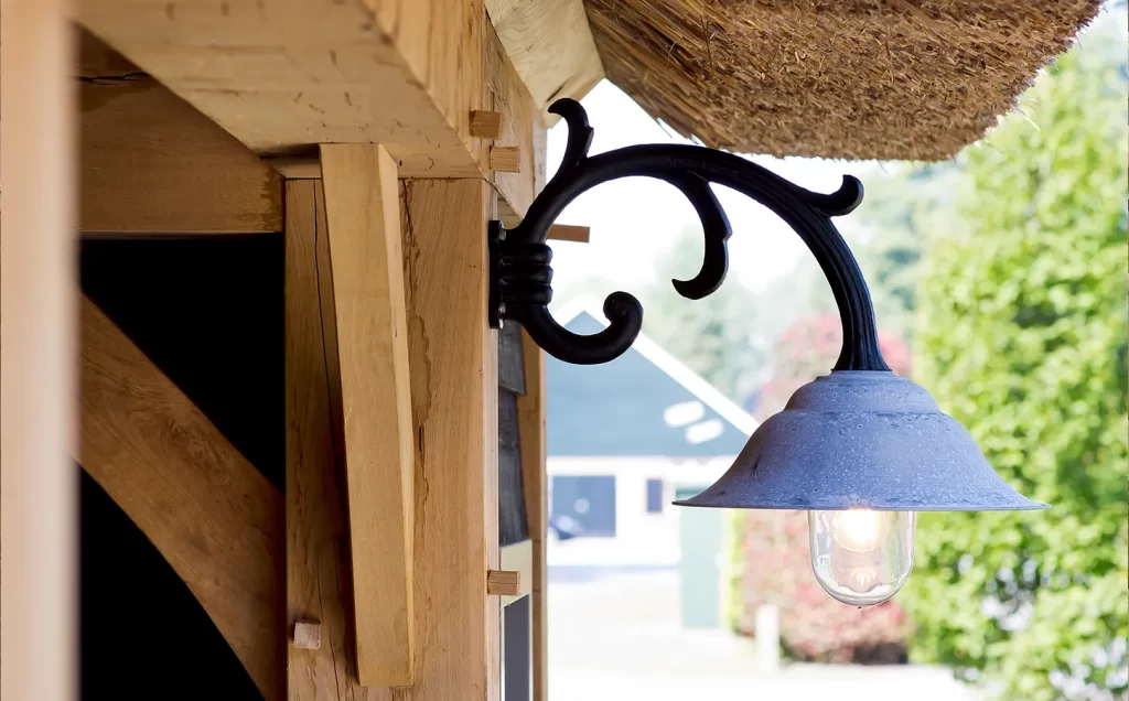 Buitenlamp aan een eikenhouten staander onder een rieten dak