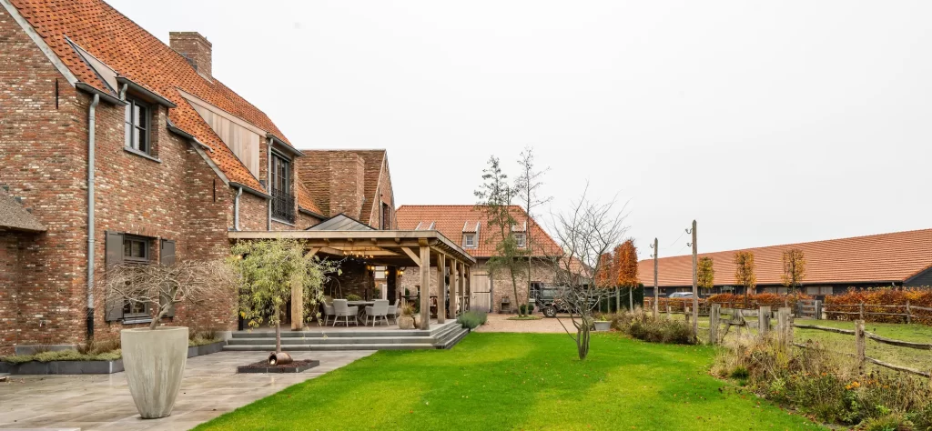 Tuin en gazon bij een bakstenen woning met een eikenhouten terrasoverkapping.